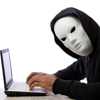 Person wearing a white mask and black hooded jacket using a laptop.