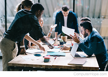 Six people meeting and talking around a table.